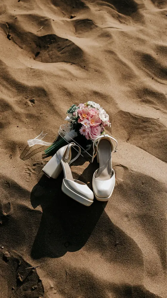 Zapatos de novia y ramo sobre la arena